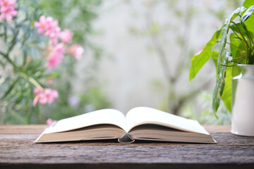 Opened old book on wooden table with romantic pink flowers background