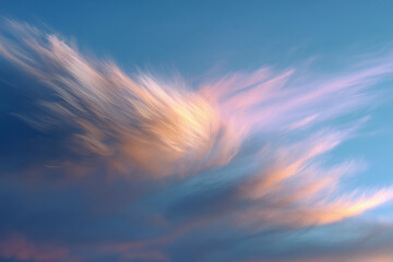 Soft pastel-colored clouds streak across a clear blue sky during a serene sunset