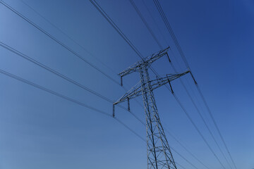 High-voltage power line tower against clear blue sky