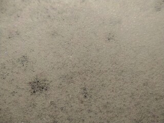 A close-up, high-angle view of white foam bubbles, creating a textured surface with tiny, interconnected spheres, possibly in soapy water.