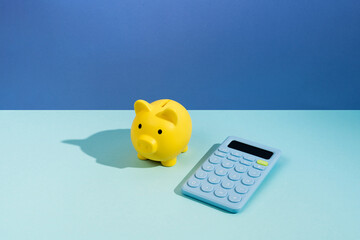 Calculator and a piggy bank on blue background