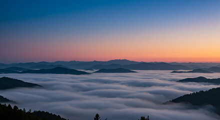 Aerial view of mountains covered in fog under a colorful sunrise sky with gradient hues and soft light