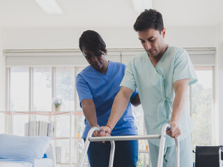 Caucasian patient man stand crutches walker with woman nurse black people carer physical therapist two person stand talk helping support give advice feel relax smile happy in room clinic hospital.