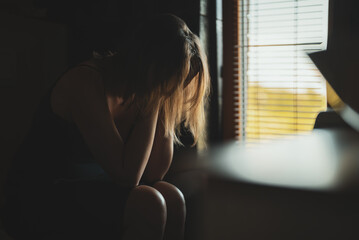 Upset woman covering face while sitting on toilet.