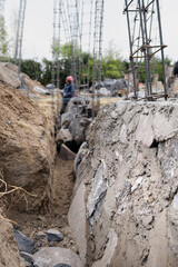 Stone foundations of a building, in the background a Latin bricklayer working