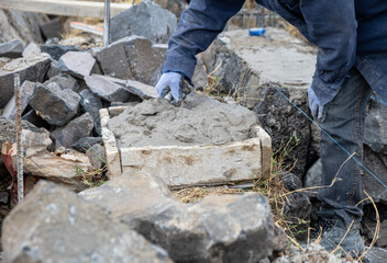 Construction worker taking mortar from a wooden trough