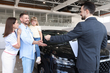 Salesman giving car key to happy family in salon
