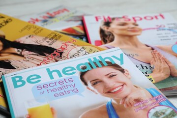 Different trendy magazines on white table, closeup