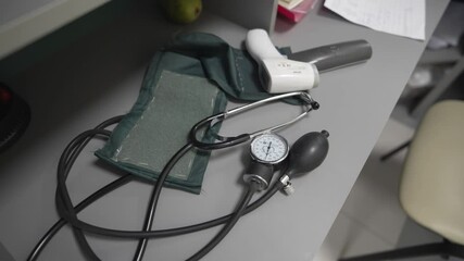 Digital thermometer and vintage blood pressure measuring device on nurse desk. Old and new medical instruments in hospital ward