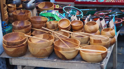 An assortment of handmade traditional wooden cutlery are displayed at a market