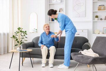 Nurse assisting senior woman indoors. Home health care service