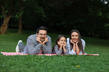 Happy family posing on checkered picnic blanket outdoors