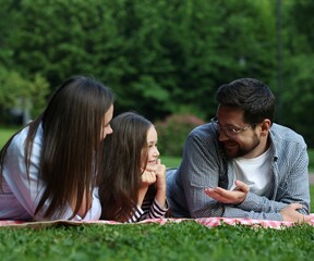 Happy family spending time together on checkered picnic blanket outdoors