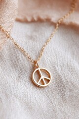 Gold peace symbol pendant necklace resting on soft beige fabric, representing harmony and unity, ideal for International Day of Peace celebrations and meaningful gifts
