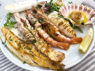 Delicious grilled seafood platter with lobster, shrimp, and scallop on a white plate