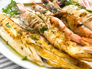 Grilled seafood platter with shrimp lobster fish lemon pepper garnish