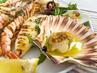 Grilled seafood platter with scallops, shrimp, and squid on lemon garnish