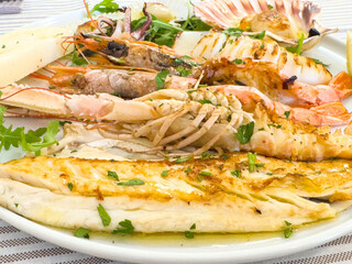Grilled seafood platter with shrimps, scallops, fish, and herbs