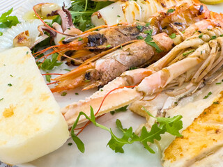 Grilled seafood platter with shrimp, squid, and cheese garnished with arugula