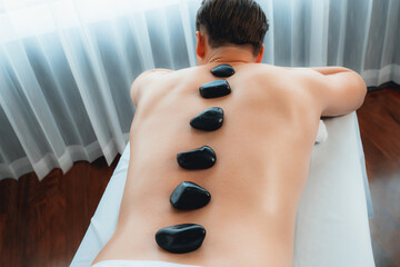 Hot stone massage at spa salon in luxury resort with day light serenity ambient, blissful man...