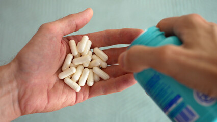 A man pours capsules of dietary supplements from a jar into his hand