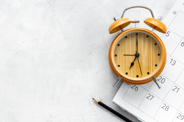 Alarm clock is on calendar with pencil, top view. Planning and time management concept