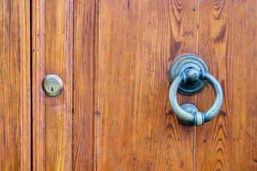Antique wooden door featuring a metallic knocker and keyhole, highlighting themes of security,...