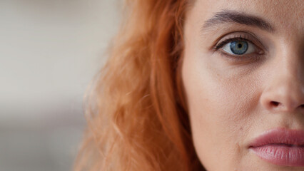Portrait half face cropped view Caucasian redhead woman looking at camera calm serious look health...