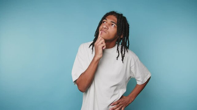 Young person deep in thought against a blue background exploring creative ideas and personal reflection at home