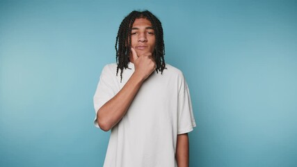 Surprised young man expresses shock while standing against a blue background
