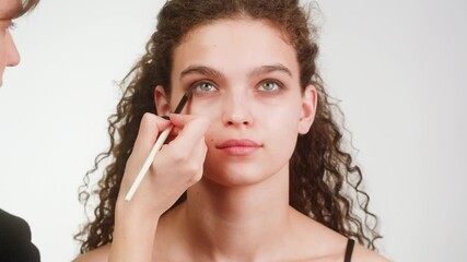 Eye shadow makeup to the upper eyelid, close-up. Makeup artist applies a bright eye shadow with a make-up brush.Tutorial master class of professional makeup, smoky eyes