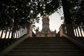 Stone stairs moving up in the park with beautiful church architecture building under sunset sky lighting. Natural colors, contrast, shadows, light