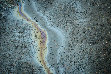 Colorful gasoline spill creating a rainbow effect on wet asphalt, highlighting environmental pollution
