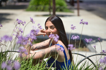 Portrait of a young woman, dark-haired, tall, slim, and very tattooed, wearing a blue top, looking...