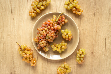 Plate full of ripe yellow grapes, top view