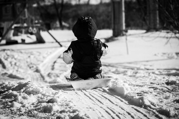 Selective focus on the snow path on the top of a hill with a child sledding down in a backyard 