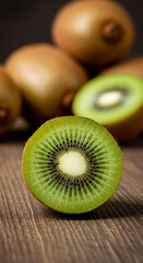 A vibrant slice of kiwi fruit is in sharp focus on a wooden surface, with whole kiwis blurred in the background