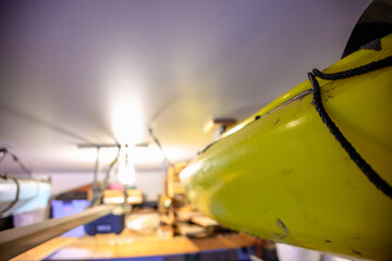 Selective focus on the side of a kayak that has used a Hoist and pulley system to store on the ceiling of a garage.