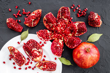 Fresh ripe pomegranate with cut in half and pieces on plate to eat, top view.