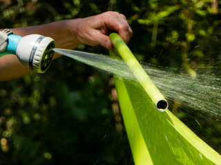 Hand holding a green fabric pole being sprayed with water
