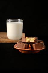 Close-Up of Sliced Chocolate-Covered Sponge Cake on Wooden Board with a glass of milk