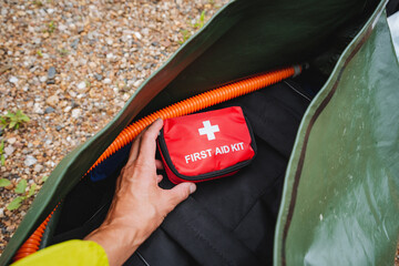 A person is holding a first aid kit that is conveniently placed inside a bag, ensuring that they...