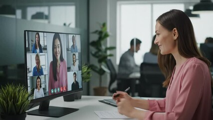 A businesswoman takes notes while participating in a virtual team meeting in a modern office. - Powered by Adobe