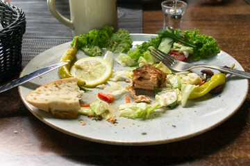 Leftover food on a plate sitting on a restaurant table.
