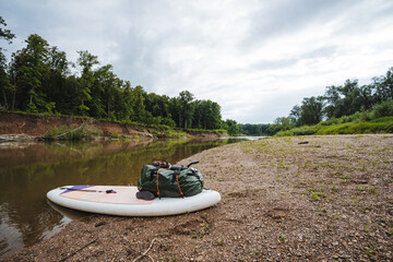 A paddle board, which is equipped with a bag resting on its surface, is currently sitting...