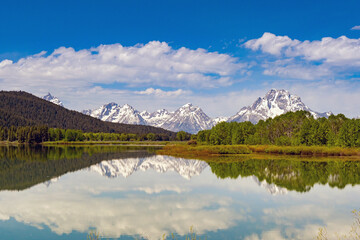 Scenic view of snow capped mountains in the Grand Teton National Park reflected in the still waters of a lake. No people.