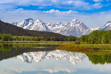 Scenic view of snow capped mountains in the Grand Teton National Park reflected in the still waters of a lake. No people.