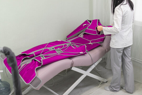 A beautician preparing a lymphatic drainage suit for a pressotherapy procedure in a wellness clinic.