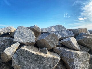 A pile of large, grey rocks fills the foreground under a clear blue sky.