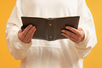 Individual presenting an empty wallet open against yellow